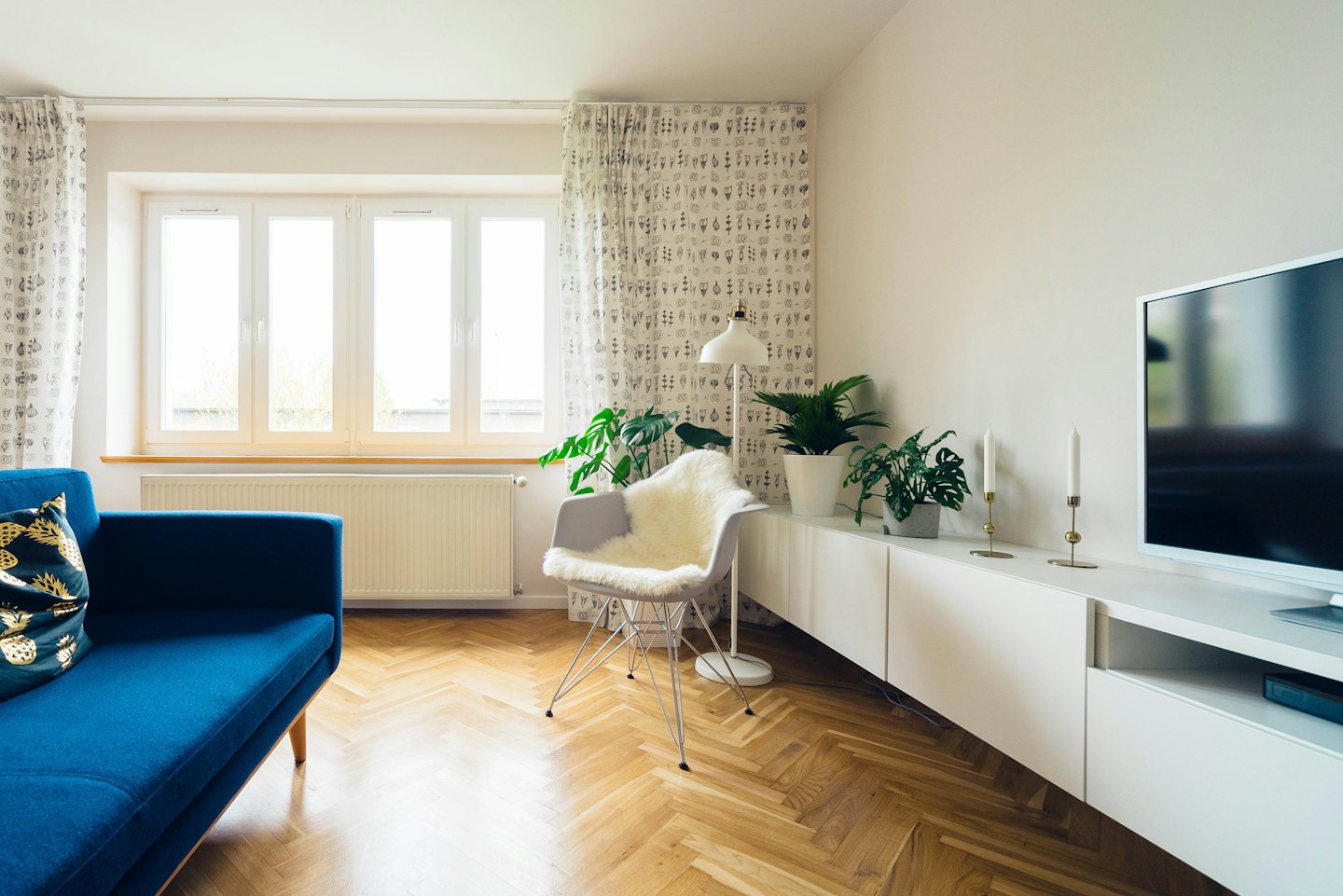 Sala de estar moderna con sofá azul y sillón blanco.